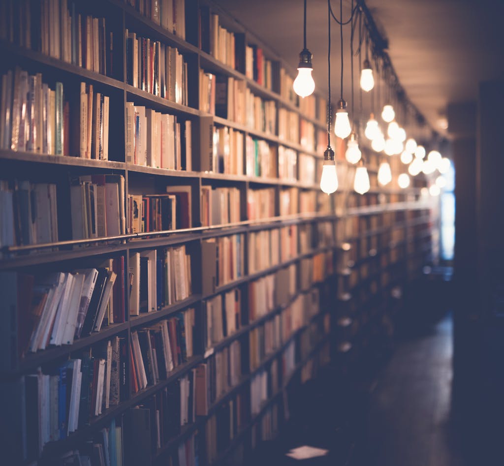 Rows of bookshelves in a cozy library with warm ambient lighting. Perfect for learning and knowledge themes.